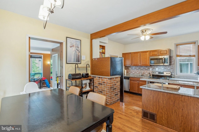 5207 Eugene Ave, Baltimore, MD 21206 - kitchen featuring appliances with stainless steel finishes, plenty of natural light, brown cabinets, backsplash, and beamed ceiling