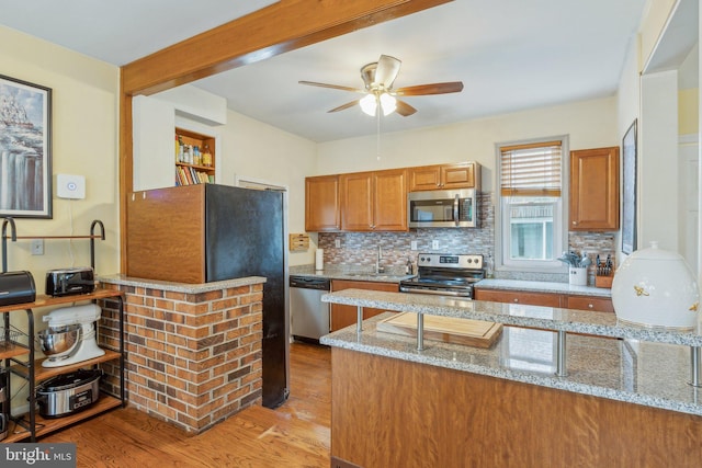 5207 Eugene Ave, Baltimore, MD 21206 - kitchen with appliances with stainless steel finishes, brown cabinetry, a ceiling fan, and light stone countertops