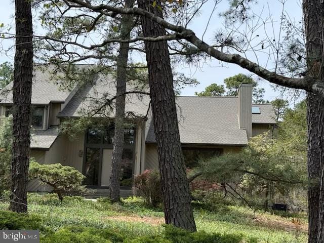 view of front of property featuring a chimney and a shingled roof