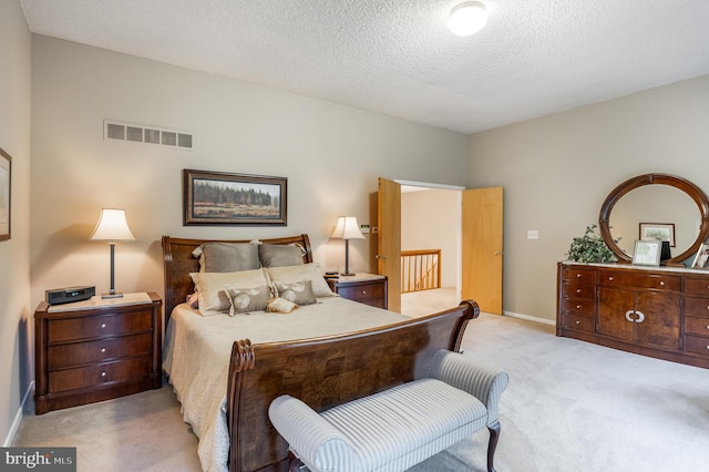 bedroom featuring light carpet, a textured ceiling, and baseboards