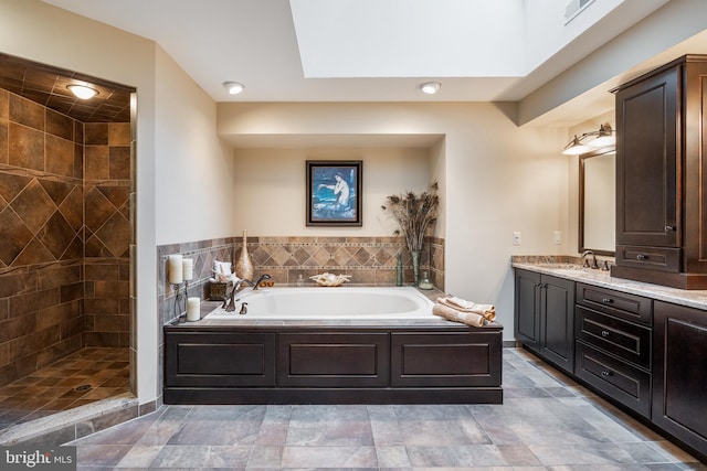 full bath featuring a bath, vanity, and a tile shower