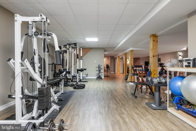exercise room featuring wood finished floors, baseboards, and a drop ceiling