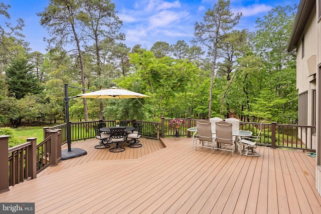 wooden terrace with outdoor dining space and view of scattered trees