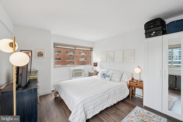bedroom with wood finished floors, a wall mounted AC, and baseboards