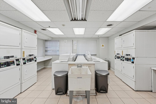 communal laundry room featuring stacked washer and clothes dryer, light tile patterned floors, and washer and dryer