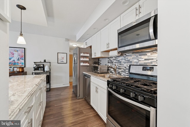 kitchen featuring appliances with stainless steel finishes, decorative backsplash, dark wood-style flooring, and white cabinetry