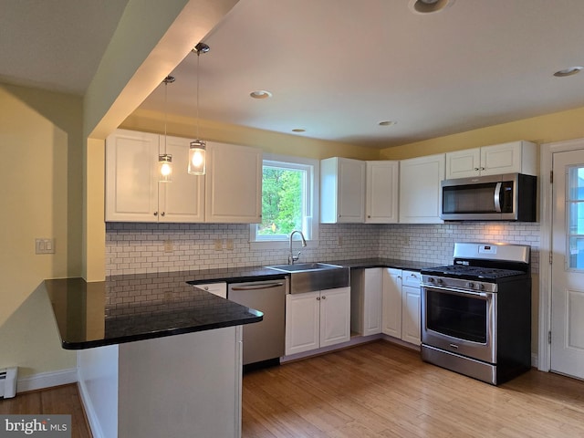 5934 Tilghman Island Rd, Tilghman, MD 21671 - kitchen featuring appliances with stainless steel finishes, dark countertops, a peninsula, a sink, and white cabinetry