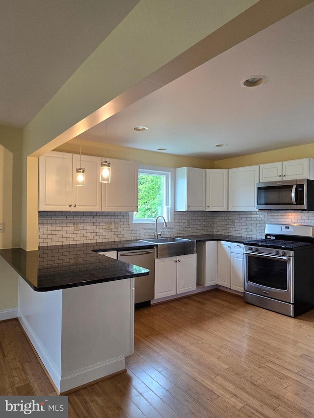 5934 Tilghman Island Rd, Tilghman, MD 21671 - kitchen featuring appliances with stainless steel finishes, a peninsula, dark countertops, a sink, and white cabinets