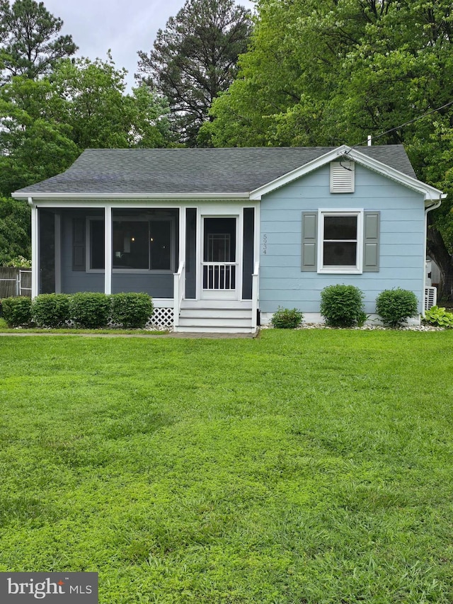 5934 Tilghman Island Rd, Tilghman, MD 21671 - ranch-style house featuring a shingled roof, a sunroom, a front yard, and view of wooded area