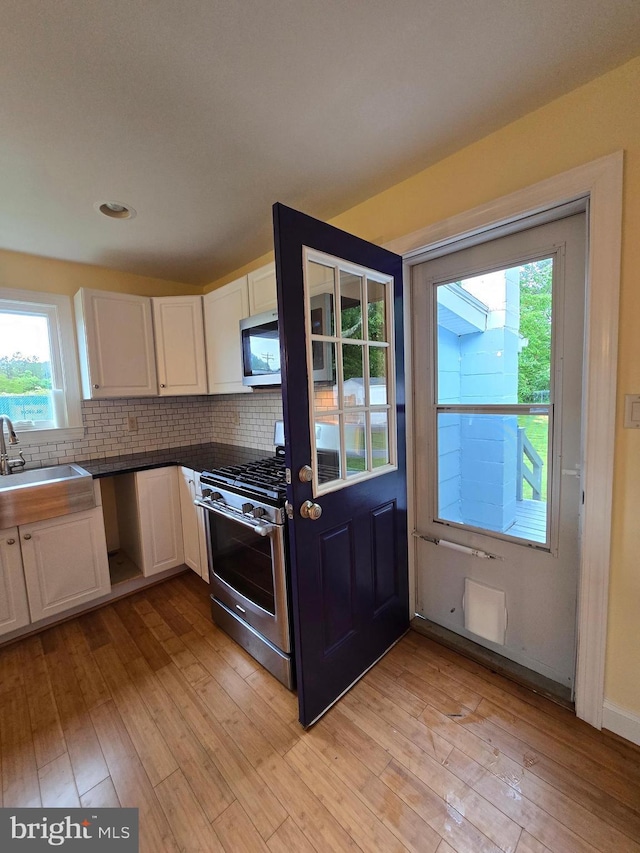5934 Tilghman Island Rd, Tilghman, MD 21671 - kitchen with stainless steel appliances, a sink, white cabinets, and light wood-type flooring