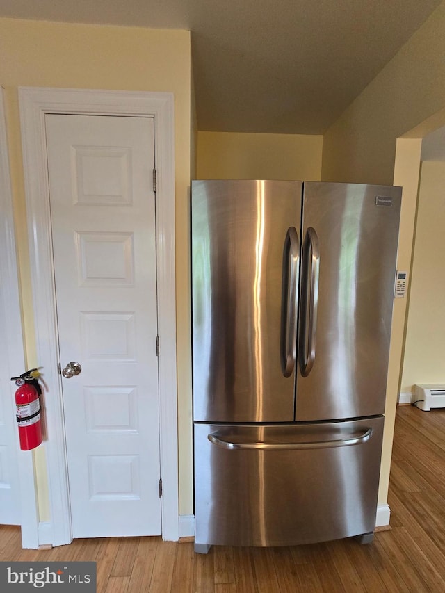 5934 Tilghman Island Rd, Tilghman, MD 21671 - detailed view of freestanding refrigerator, a fire extinguisher, a baseboard radiator, and wood finished floors