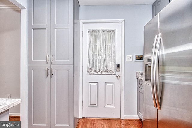 doorway to outside with light wood-style flooring and baseboards