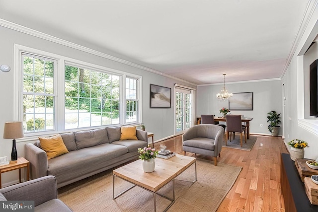 living room with crown molding, a chandelier, light wood-style flooring, and baseboards