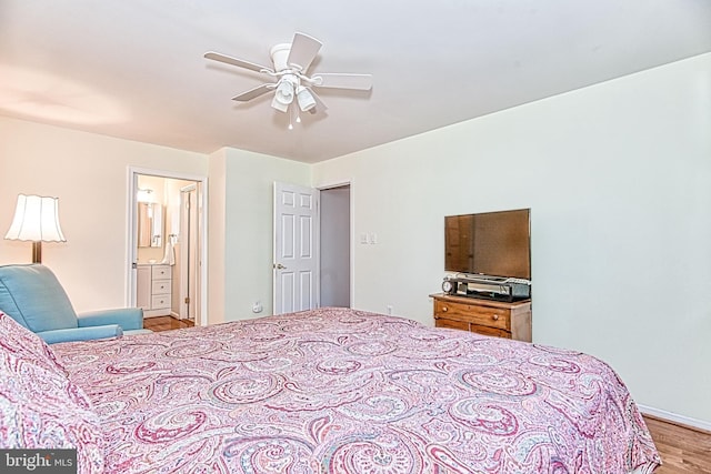 bedroom with wood finished floors, connected bathroom, baseboards, and ceiling fan