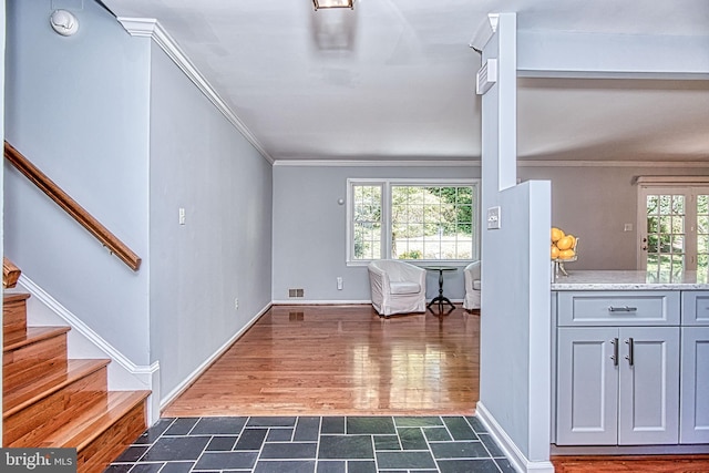 unfurnished living room featuring ornamental molding, stairs, dark stone finish flooring, and baseboards