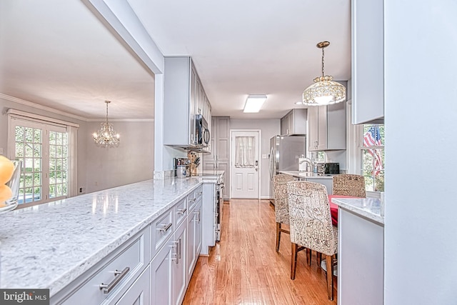 kitchen featuring light wood-style flooring, gray cabinetry, light stone counters, a chandelier, and ornamental molding