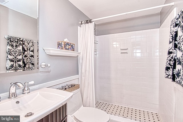 bathroom with toilet, tiled shower, and vanity