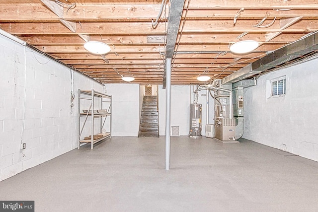 unfinished below grade area with water heater, heating unit, stairs, and concrete block wall