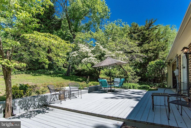 wooden deck featuring outdoor dining space and view of scattered trees