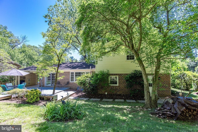 rear view of house with brick siding, a yard, and a deck