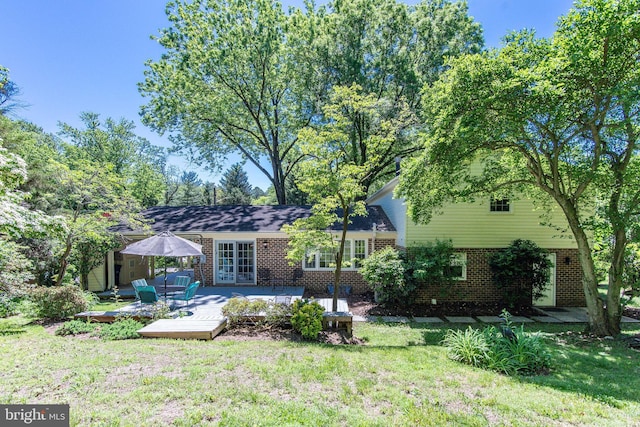 rear view of property with brick siding, a yard, and a wooden deck