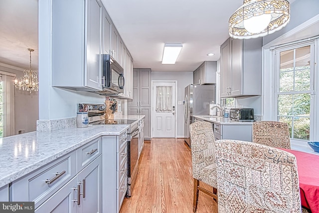 kitchen with stainless steel appliances, gray cabinets, light wood-style flooring, a chandelier, and ornamental molding