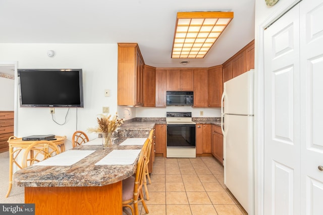105 120th St Unit 87, Ocean City, MD 21842 - kitchen with electric range, black microwave, freestanding refrigerator, a peninsula, and a breakfast bar area
