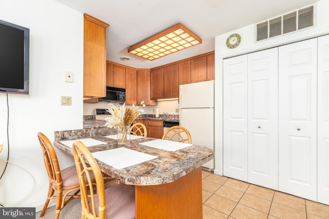 105 120th St Unit 87, Ocean City, MD 21842 - kitchen with freestanding refrigerator, black microwave, a peninsula, light tile patterned floors, and a kitchen breakfast bar