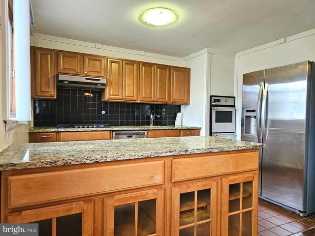 1506 N 13th St, Philadelphia, PA 19122 - kitchen featuring stainless steel appliances, under cabinet range hood, brown cabinets, tasteful backsplash, and light stone counters
