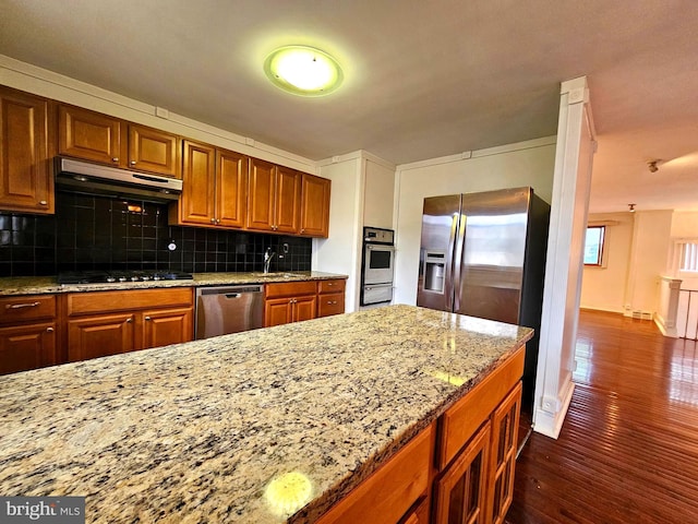 1506 N 13th St, Philadelphia, PA 19122 - kitchen featuring stainless steel dishwasher, under cabinet range hood, dark wood-style floors, brown cabinets, and backsplash