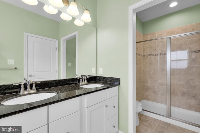 full bath with a stall shower, double vanity, toilet, and tile patterned flooring