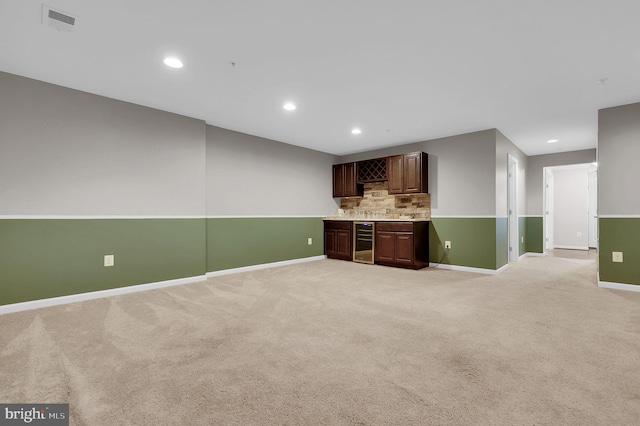 indoor wet bar featuring wine cooler, baseboards, light carpet, tasteful backsplash, and recessed lighting
