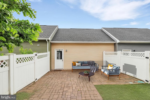 back of house featuring a patio, outdoor lounge area, roof with shingles, and a fenced backyard