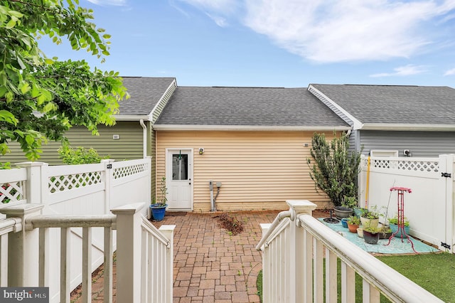view of side of home with roof with shingles, a fenced backyard, a patio, and a garage