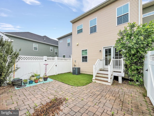 rear view of property featuring a gate, a patio area, a fenced backyard, and central AC unit