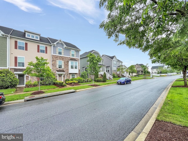 view of asphalt street featuring a residential view, curbs, and sidewalks