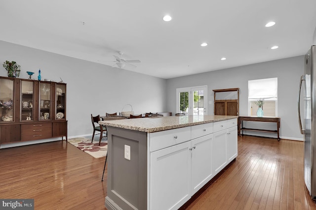 kitchen featuring freestanding refrigerator, a kitchen island, hardwood / wood-style floors, a ceiling fan, and recessed lighting