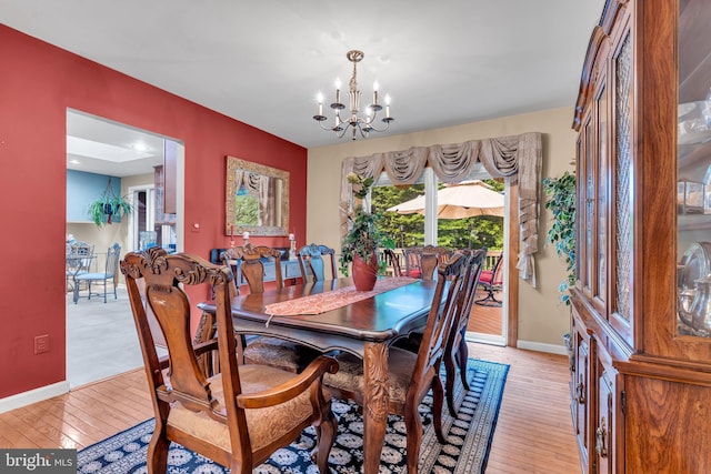dining space with a chandelier, light wood-style flooring, and baseboards