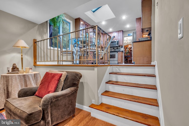 staircase with a skylight, wood finished floors, and recessed lighting
