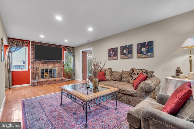 living room with wood finished floors, baseboards, recessed lighting, and a brick fireplace