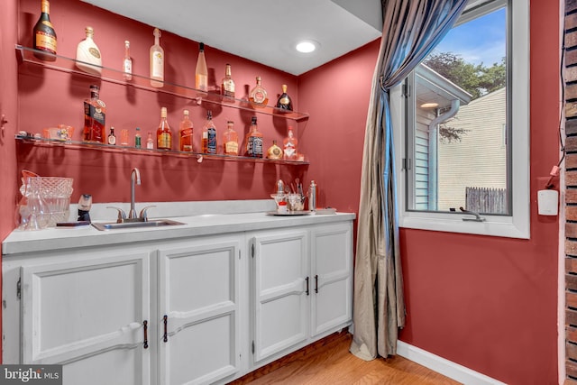 indoor wet bar featuring light wood-style flooring and baseboards