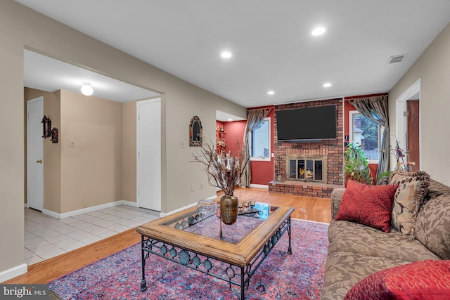 living area featuring wood finished floors, a brick fireplace, recessed lighting, and baseboards