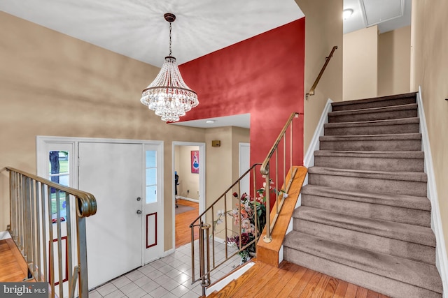 foyer entrance featuring a high ceiling, stairway, baseboards, wood finished floors, and a chandelier