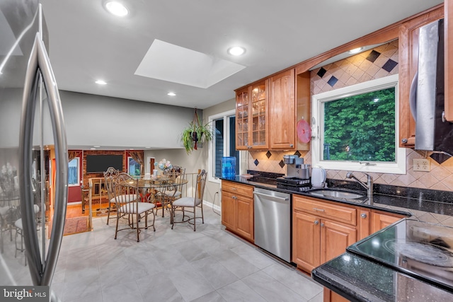 kitchen with stainless steel appliances, a skylight, a sink, backsplash, and recessed lighting