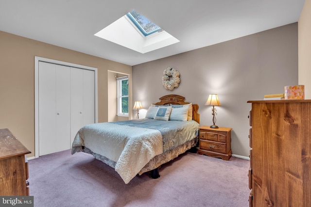 carpeted bedroom with a skylight, a closet, and baseboards
