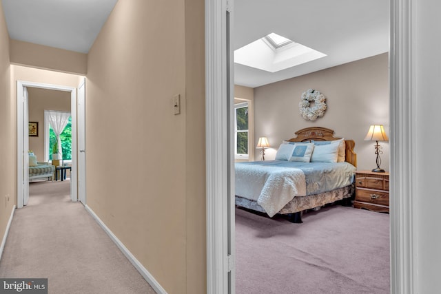 bedroom with a skylight, carpet flooring, multiple windows, and baseboards