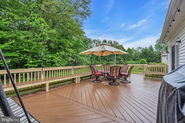 wooden deck featuring view of wooded area and outdoor dining area