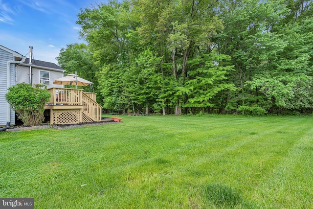 view of grassy yard featuring a wooden deck and stairs