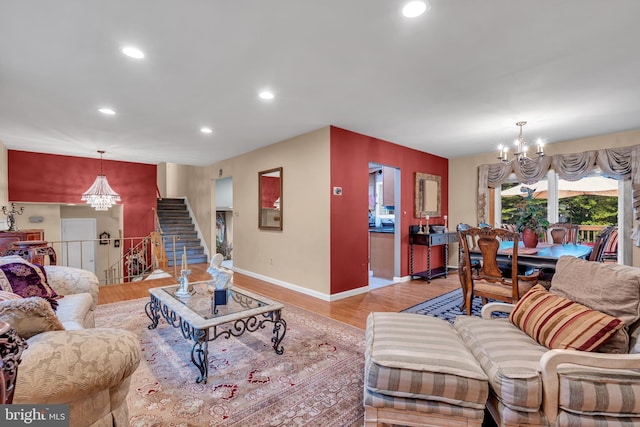 living room with a chandelier, recessed lighting, light wood-style floors, baseboards, and stairway