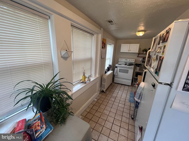 619 S Cameron St, Winchester, VA 22601 - kitchen featuring white appliances, radiator, a textured ceiling, light tile patterned floors, and white cabinets